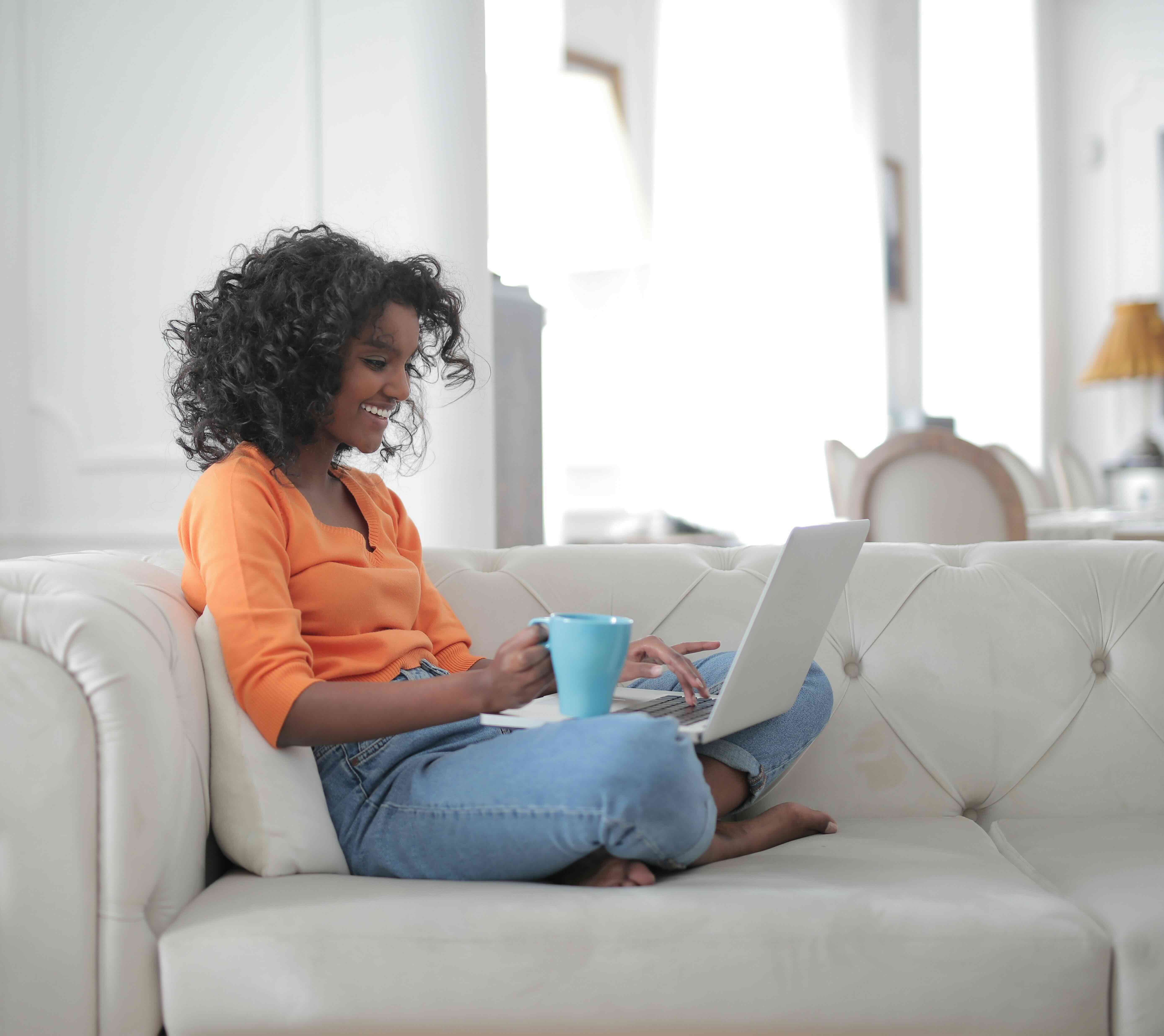 Woman using a laptop while sitting on the couch.